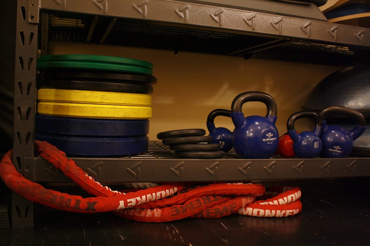 Weight plates, kettlebells and a battle rope on the clinic's equipment rack