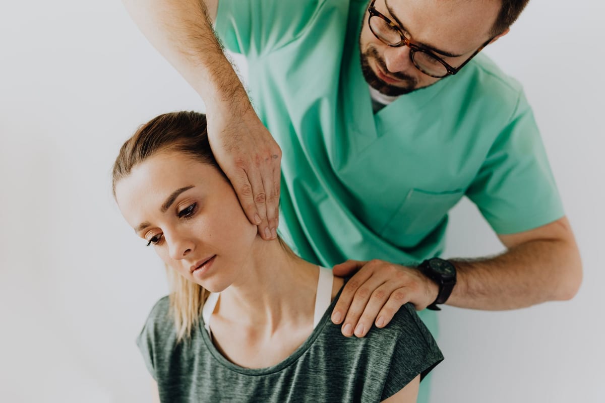 A clinician taking a seated patient's neck through a gentle range of movement